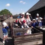 pupils and teacher on a school trip to a mine , they are all wearing hard hats