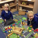 young pupils sitting on the floor playing with lego