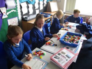 pupils sitting at desks working on a lesson that includes coloured blocks