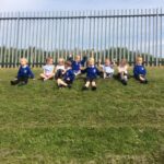 young pupils sitting at the top of a hill in the playground and laughing