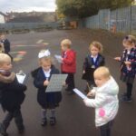 young pupils outside in the playground using clipboards and a key to find items