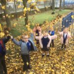 pupils outside throwing leaves up in the air on an autumn day