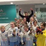 pupils dresed in sports trip all holding trophies and cheering with hands in the air