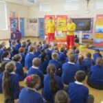 pupils sitting on the floor and listening to visitors talking about water safety